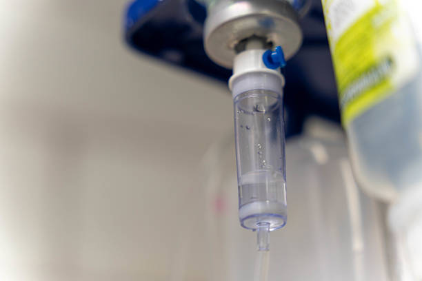 Saline solution dripping through a drip chamber, providing intravenous therapy in a medical environment