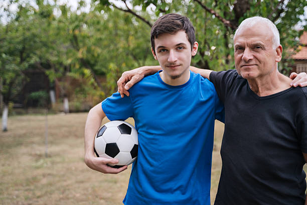 The young man and older man pose together with a soccer ball, highlighting the close friendship and generational bond formed through their shared interest in soccer.