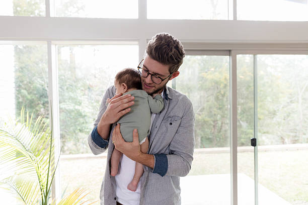 istock Tender moment: Father cradling his baby near window 2233885075