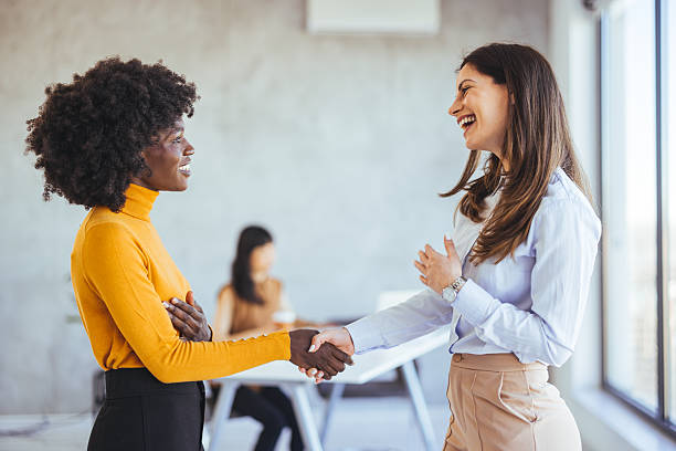 istock Two Women Smiling and Shaking Hands in a Modern Office Setting 2233887147