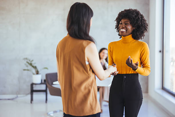 istock Two Women Smiling and Greeting Each Other in a Modern Office Setting 2233887151