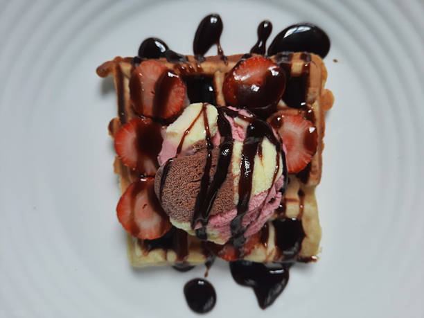 waffle with ice cream and chocolate syrup on a white plate.