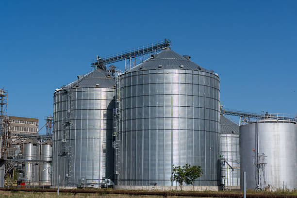 istock Grain storage silos and large warehouse hangars under clear blue sky 2233900133