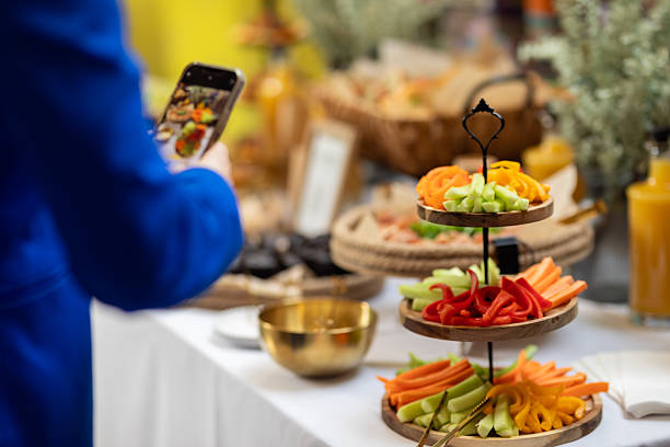 istock Professional caterer photographing vibrant vegetable platter using smartphone during event, displaying appetizing catering selection 2233902267