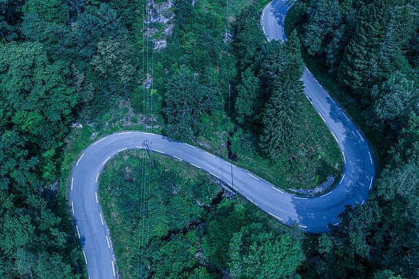 istock Curving road through lush green forest aerial. 2233904362