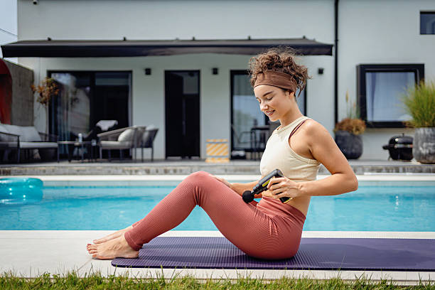 istock Young woman using a massage tool by the pool for recovery 2233908130