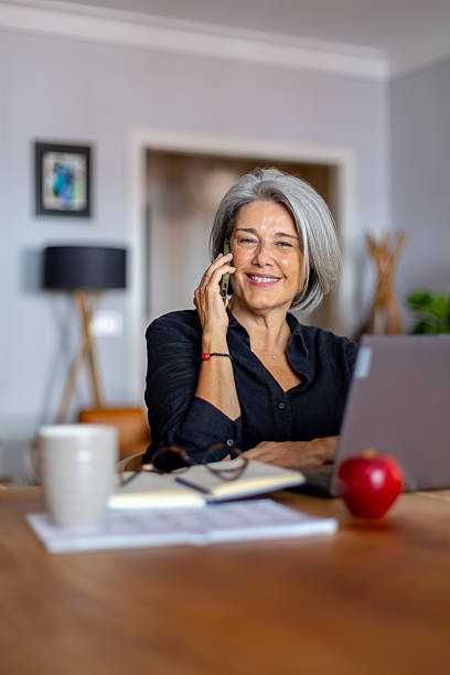 istock Smiling senior freelancer working from home office talking on phone 2233918333