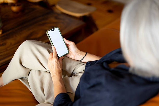 istock Senior woman relaxing on sofa using smartphone with blank screen 2233918342