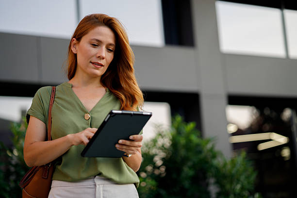 istock Professional female working on digital tablet near sleek corporate architecture, representing mobile technology in contemporary business setting 2233920336