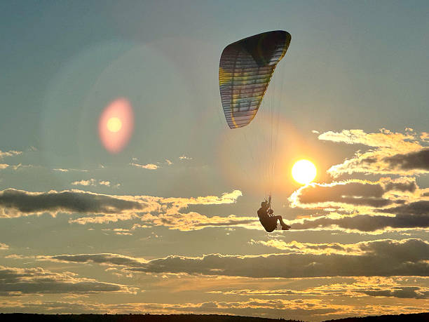Para-glider in silhouette sails through blue skies