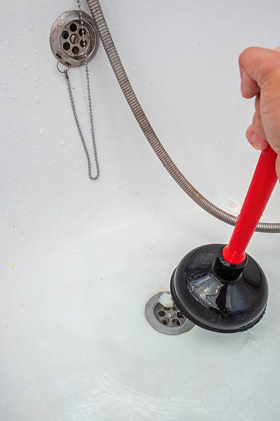istock Person Using a Plunger to Unclog Bathtub Drain 2233949284