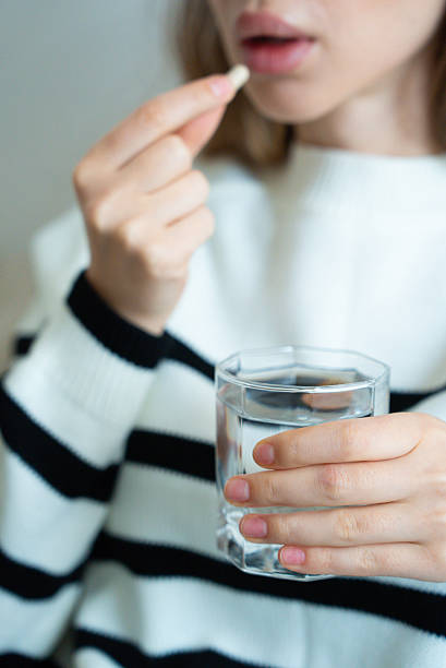 istock Woman preparing to take medicine with water 2233949559