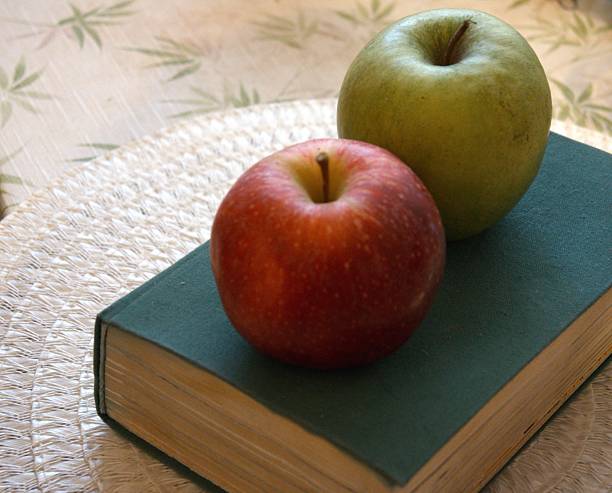 istock Red and green apples on thick green book 2233951095