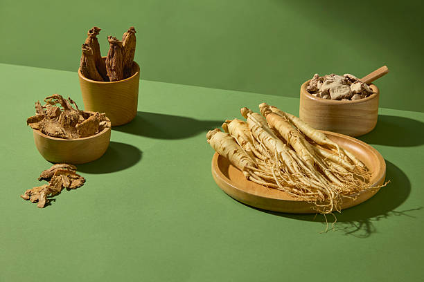 istock Horizontal composition showing fresh ginseng roots, dried red ginseng and herbs placed on a green surface. Wooden containers add a natural and rustic feeling. Space for design 2233952305