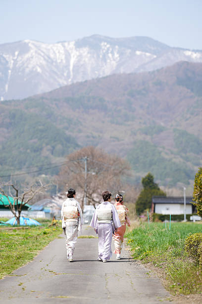 Three women walking down a road in front of a mountain