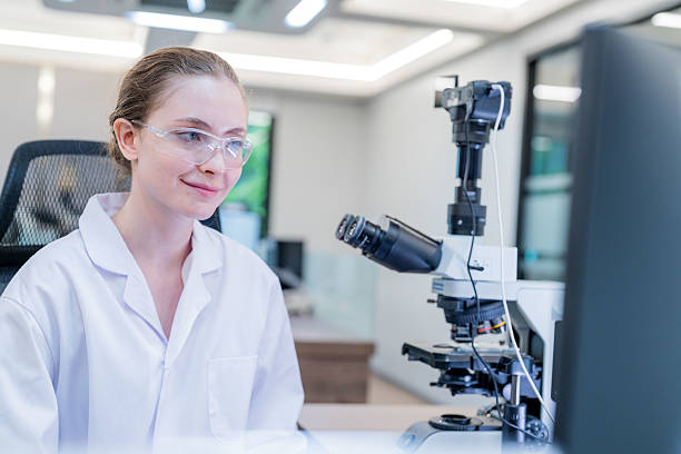istock Scientist working at microscope in modern laboratory with digital screens nearby 2233955716