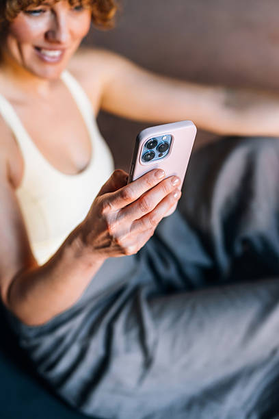 istock Woman Relaxing Indoors While Holding Smartphone in a Casual Setting 2233956960