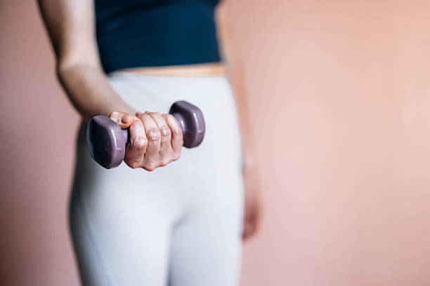 istock Woman Holding Dumbbell Engaged in Exercise Against a Minimalist Background 2233956977