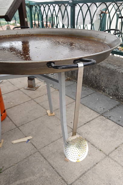 istock Large paella pan resting on metal support with skimmer 2233959021