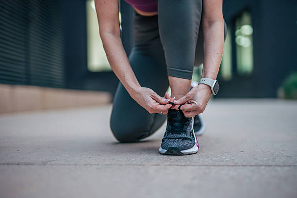 istock Female athlete tying shoelaces before running in urban setting 2233961194