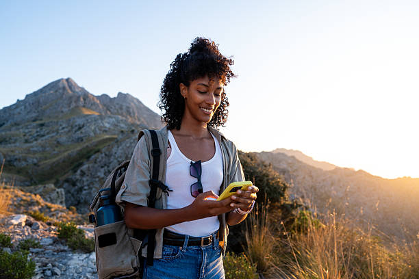 Female tourist using her smartphone during a mountain hike in the Sierra de Tramuntana, Majorca. Concept of lifestyle, travel and digital connection in the Balearic Islands.