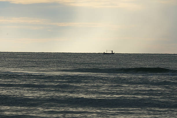 The scenery of the sea and the little boat are further away. Contrast with the cloudy sky.