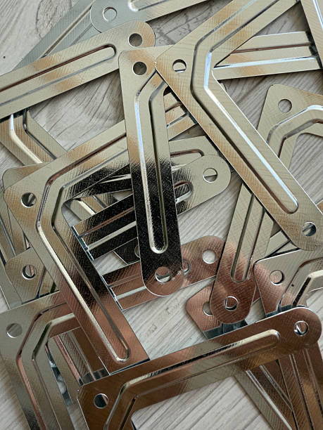 Shiny metal brackets with holes resting on a wooden table, showcasing their readiness for various construction and repair projects