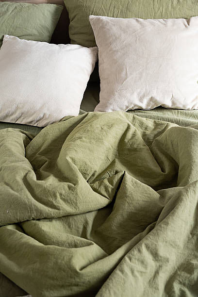 istock Crumpled green bedding with white pillow on bed. 2233964608