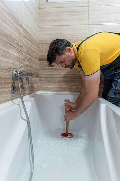 istock Man unclogs bathtub drain with a plunger in a modern bathroom setting 2233965062