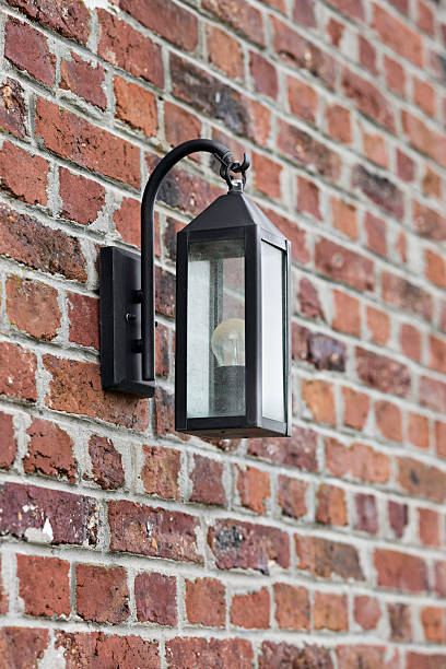 A classic black outdoor lantern mounted on a rustic red brick wall. The traditional light fixture adds a decorative touch to the home's exterior.