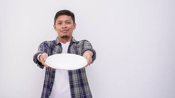 istock Asian man looking to empty plate and holding spoon and fork isolate on white 2233968354