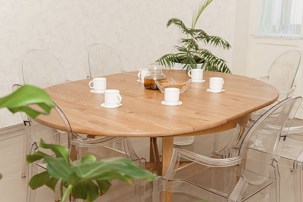 istock Cozy dining setting featuring a round wooden table surrounded by transparent chairs, complemented by lush green potted plants, creating a warm and inviting interior atmosphere. 2233969944