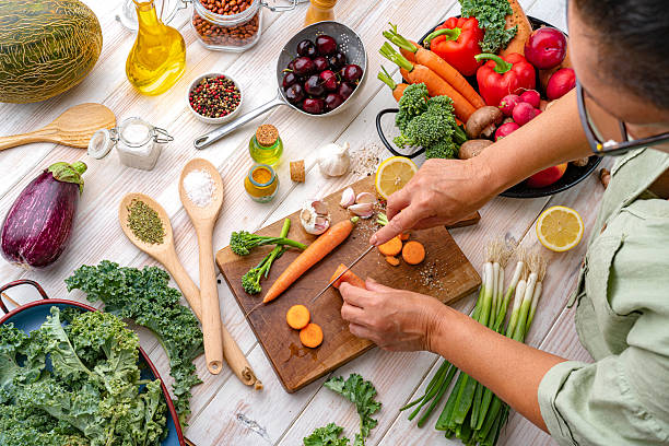 Woman is preparing vegetarian meal. Chopping food in the kitchen. Fresh organic ingredients for a healthy and tasty meal. Slicing carrots