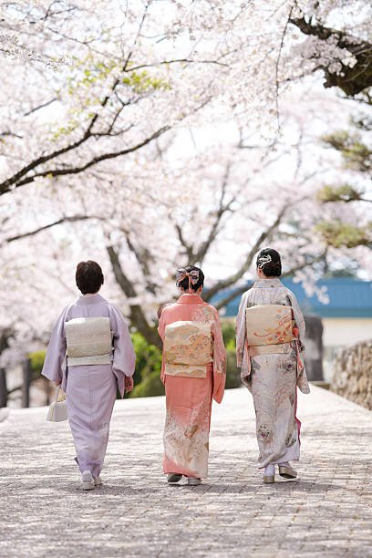 Three women in traditional Japanese clothing walk down a path