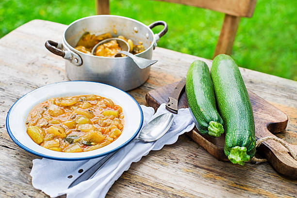 Eating Slovenian traditional dish with zucchini sauce in red. Freshly picked zucchini from the garden. Summer food