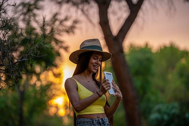 istock Woman taking a selfie in a park at sunset. 2233976178