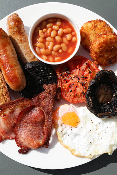 istock Image of full english fried breakfast on white plate, sausages, bacon, eggs, black pudding, mushrooms, toast, baked beans, hashbrowns 2233979459