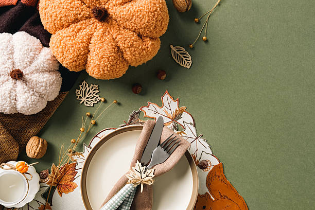 istock Autumn table setting with fabric pumpkins, plate, napkin, silverware, leaves, acorns, and walnuts on green background 2233982609