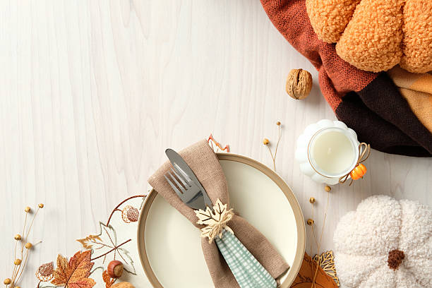 istock Festive autumn table setting with plate, cutlery with maple leaf ring, pumpkins, layered napkins, , nuts, and cozy blanket. Thanksgiving dinner concept. 2233982929