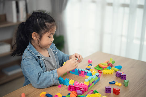 istock Creative Child Engaged in Imaginative Play with Colorful Building Blocks on a Table in Bright Room with Natural Light Filtering Through Window 2233985343