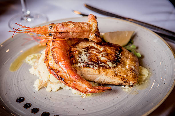 Elegant seafood presentation featuring perfectly grilled shrimp served alongside a fish fillet and garnished with lemon wedges.