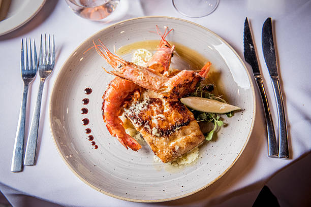 A deliciously presented seafood dish featuring grilled fish filet and shrimp, complemented by a lemon wedge and fresh greens. Ideal for restaurant promotions, recipe inspiration, or culinary showcases. The combination of gourmet preparation and elegant plating makes it a visual treat for food enthusiasts and aspiring chefs.