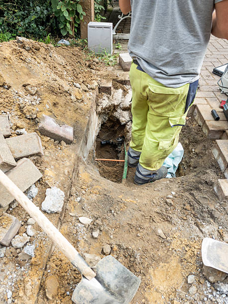 istock Workers wearing yellow work trousers are digging a hole to disconnect utilities such as gas and electricity. Concrete pavers lie in a pile. 2233994057