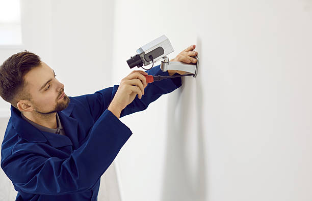 istock Male technician installs video surveillance camera on wall inside office for security. 2233994431