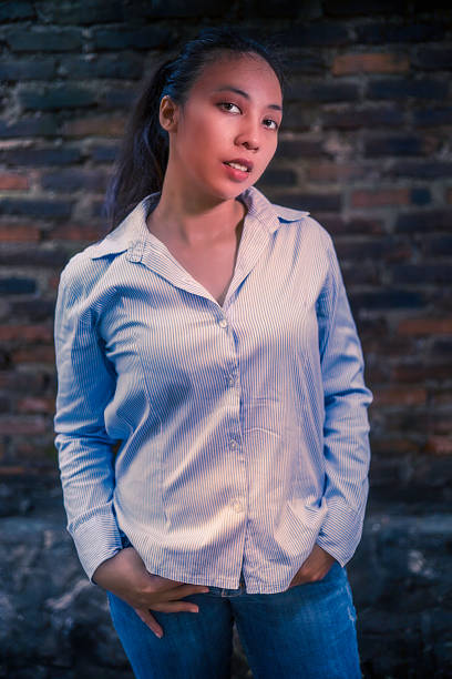 Indonesian girl posing in jeans by an old brick wall