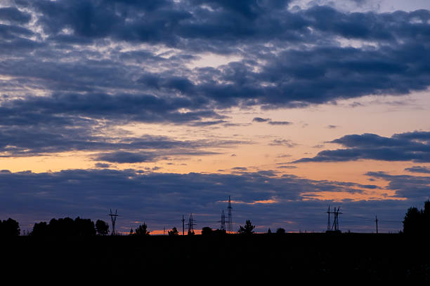 The sky is dark and cloudy with a beautiful orange sunset. The clouds are low and the sun is setting, creating a peaceful and serene atmosphere