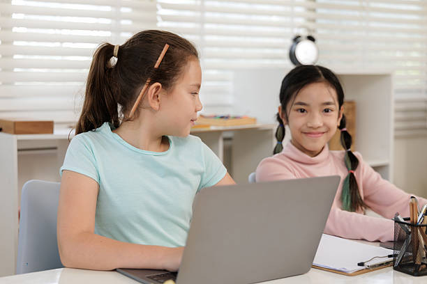 istock Two girls are intently focused on their online class in a classroom or at home, 2234010507