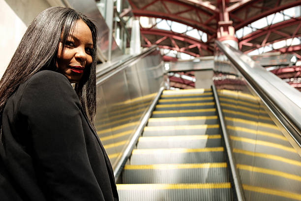 istock Businesswoman ascending escalator in modern transportation hub 2234012814