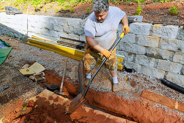 Laborer uses shovel to dig trench in garden for an outdoor new drainage system project on work day.