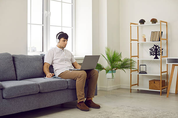 istock Man using his laptop computer while sitting on a comfortable sofa in the living room 2234018139